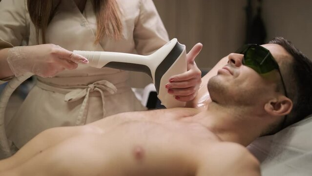 A man undergoing a laser hair removal treatment on his chest with a professional technician in a clinic