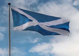 Scottish flag fluttering against blue sky