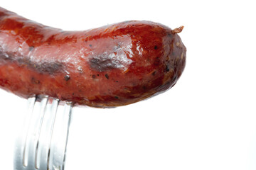 Grilled precook smoke beef sausage on a fork isolated on white background