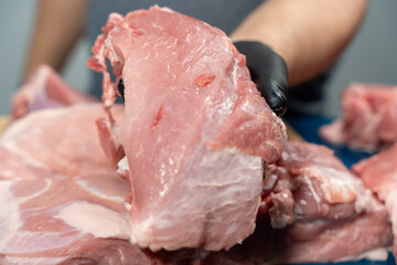 A man in black latex gloves cuts pork on a cutting board. Pork meat close-up.