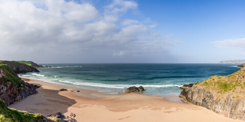 An expansive panorama of Durness Beach, Scotland, where the contrast between the lush green cliff tops and the golden sandy beach is highlighted by the vivid turquoise of the Atlantic