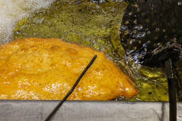 Pizza fritta tradizionale napoletana ripiena di ricotta, pepe e cicoli di maiale mentre viene fritta nell'olio bollente