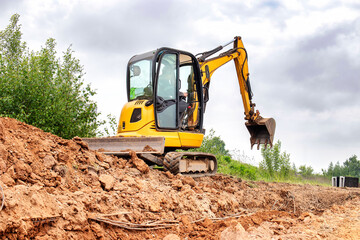 A excavator actively digging through a mound of soil and dirt, creating a path and clearing the area © Anoo