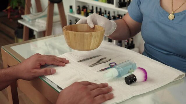 Latin manicurist present show instruments in front of male muscle cliente before manicuring procedure nail polish at wellness center spa hotel