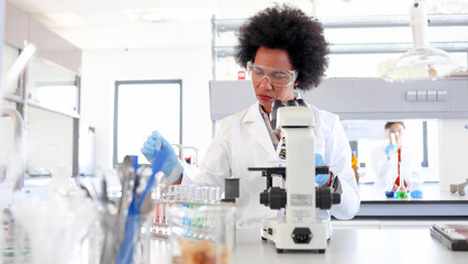 African American female scientist working at the lab and examining some samples on the microscope