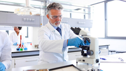 Mature lab specialist examining something on the microscope