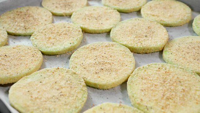 Slices of white zucchini in breadcrumbs and seasonings lie on the deco. Zucchini dish, zucchini recipe, vegetarian food, quick snack, party. Close-up, side view, camera moving plano