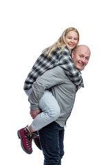A young girl sits on the back of a bald man. Cute laughing blonde girl in a black and white checkered shirt and jeans and a guy in a gray shirt. 
