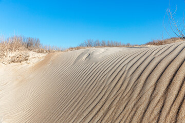 Sand dune against the blue sky. Beautiful coastal landscape.