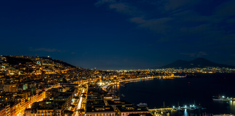 beautiful night panorama of Naples city with nice lights streets flashlights and buildings and volcano Vesuvius with amazing sky on background