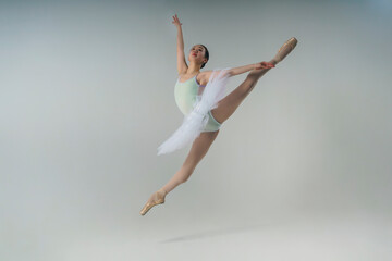 young Japanese ballerina in a photo studio does a grand jete splits in a jump © Alex