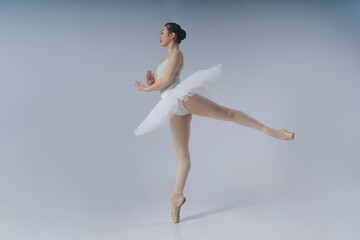 young Japanese ballerina in a photo studio makes an arabesque showing balance and plasticity