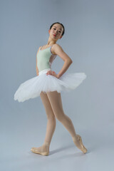 young Japanese ballerina poses in a photo studio with ballet elements showing stretching and plasticity