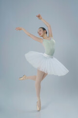 Fototapeta na wymiar young Japanese ballerina poses in a photo studio with ballet elements showing stretching and plasticity