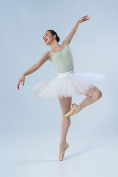 young Japanese ballerina poses in a photo studio with ballet elements showing stretching and plasticity