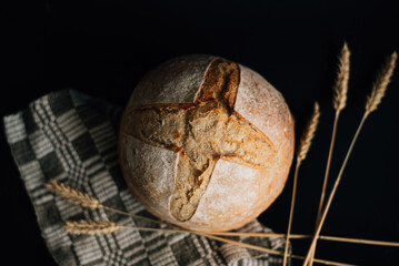 loaf of fresh bread and spikelets on a black background