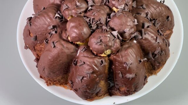 Chocolate panettone with profiteroles on dish on a gray background