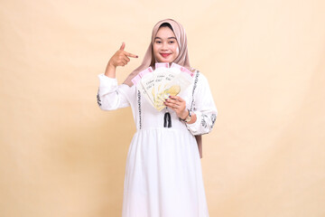 portrait of a beautiful Asian Muslim girl wearing a hijab with a graceful smile showing gifts and gifts on Eid. used for advertising, giveaways, Eid and Ramadan