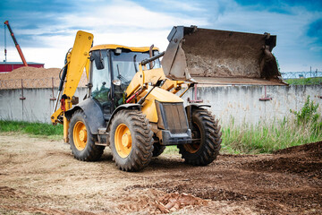 A yellow bulldozer or a loader is parked next to a building, ready for construction work