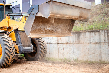 Fototapeta na wymiar A yellow bulldozer or a loader is parked in front of a building, ready for construction work