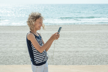 Girl is blogger on the beach with telephone.	