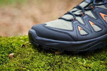 Sturdy hiking boots on vibrant green moss. Trekking shoes in nature. Concept of exploration and...