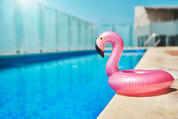 Pink pool float flamingo by blue water, pool party toy. Inflatable Swimming Ring. Summer vacation holiday luxurious resort.