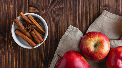 Red apples on a wooden background with cinnamon