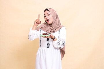 a beautiful indonesia Muslim woman wearing a hijab was surprised to point upwards and bring dates for the sahur menu and breaking the fast. used for advertising, health, Eid and Ramadan