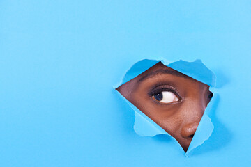 Tear, hole and eye of person on blue background for vision, eyesight and looking for inspiration....