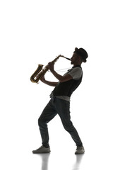 Talented young man making creative performance, playing saxophone isolate don white background. Black and white image. Concept of music, festival, concert, entertainment, instruments. Poster, ad
