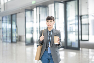 Fototapeta premium White-collar workers carrying coffee to work in the morning walk into the lobby of the office building