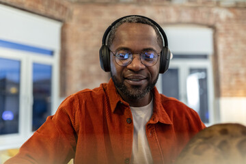Dark-skinned man in eyeglasses working at home