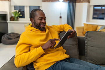 African american man in yellow hoodie with tablet in hands