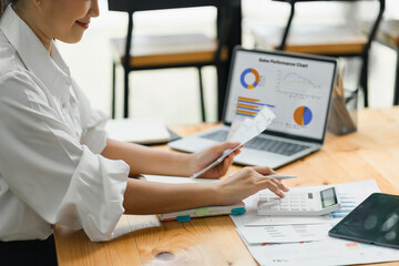 A businesswoman or accountant using laptop to analyze financial investments and business and...