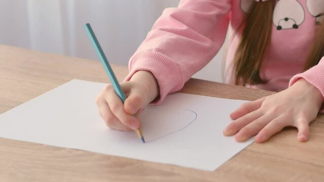 The child's hand, accustomed to holding a pencil, draws correctly on paper. The development of preschool children. The correct grip of a writing pen.