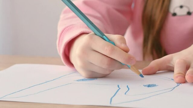 The correct grip of the pencil. A small preschool child draws on a piece of paper. A habit developed by a silicone pencil attachment.