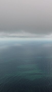 Aerial vertical view. Dramatic moody and gloomy rain clouds over sea. Abstract aerial nature summer ocean sunset sea and sky. Horizon. Vacation, travel and holiday concept. Weather and climate change