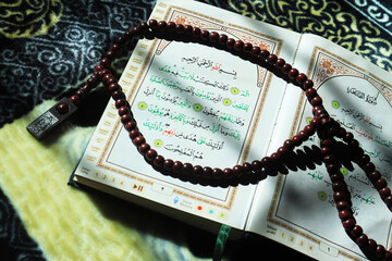 The holy book Al Quran for Muslims. Al-Quran on a prayer mat and prayer beads