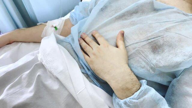 Intravenous morphine infusion for suffering patient lying on hospital bed in disposable surgical gown, medical treatment for patient losing hope in future, support of patient approaching to death