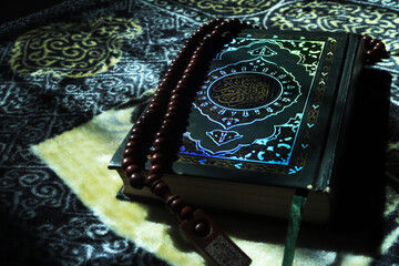 The holy book Al Quran for Muslims. Al-Quran on a prayer mat and prayer beads