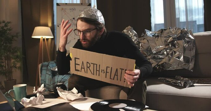 Pseudoscience and conspiracy theory. A man in a tinfoil hat proves the flat earth theory.