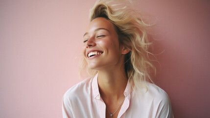 Portrait of beautiful young woman with blond hair smiling on pink background