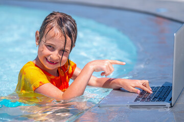 Funny portrait of business girl working distance on laptop. Pretty young lady typing on computer in the waterpool. Freelance, remote work on vacation.