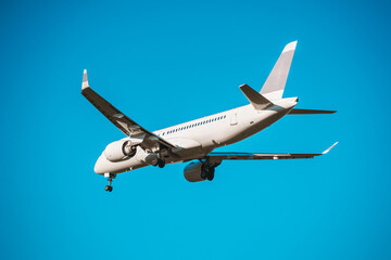 Rear view of a landing airplane in the blue sky.