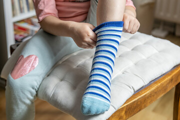 close-up of female 4-year-old child, Preschooler learning to dress independently, putting on blue...