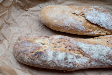 Two baguettes on a background of kraft parchment. French bread. View from above. Bread on a board. Loaf of bread.