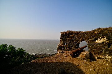 Old war cannon lying among the ruins of Korlai fort. A naval defense fortress depicting Portuguese...