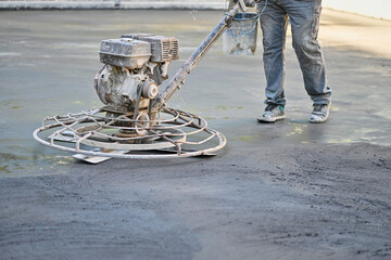 Unrecognizable worker operates a concrete polishing machine at the floor renovation site in a...