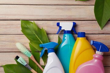 Spring cleaning concept with colorful detergent bottles and brushes amid green leaves. 
